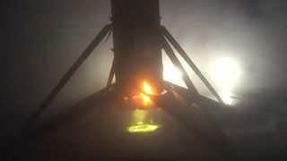 обугленная ракета стоит вертикально на плоской барже, освещенной огнями в утреннем тумане